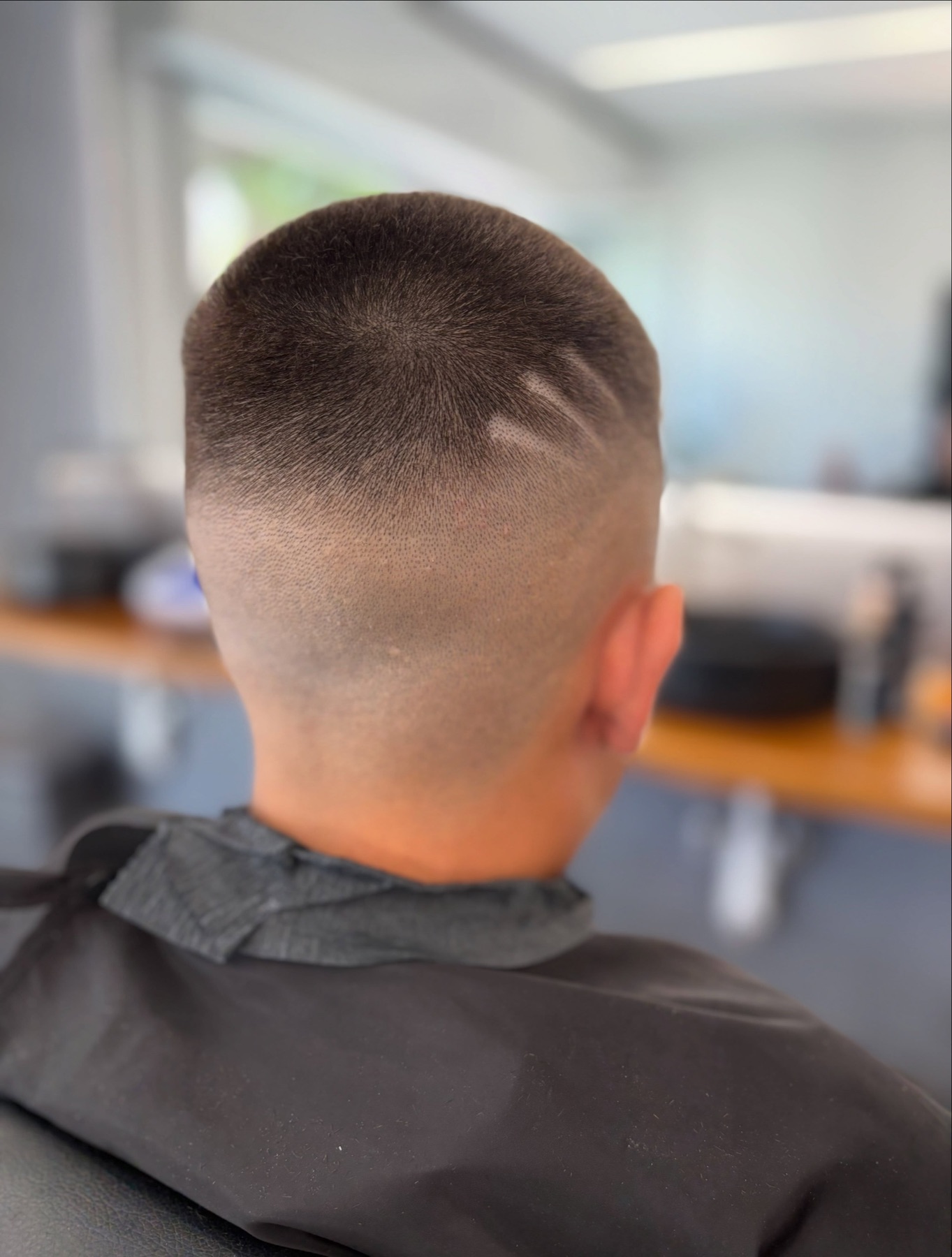 Vista posteriore di un buzz cut sfumato realizzato su un giovane cliente
